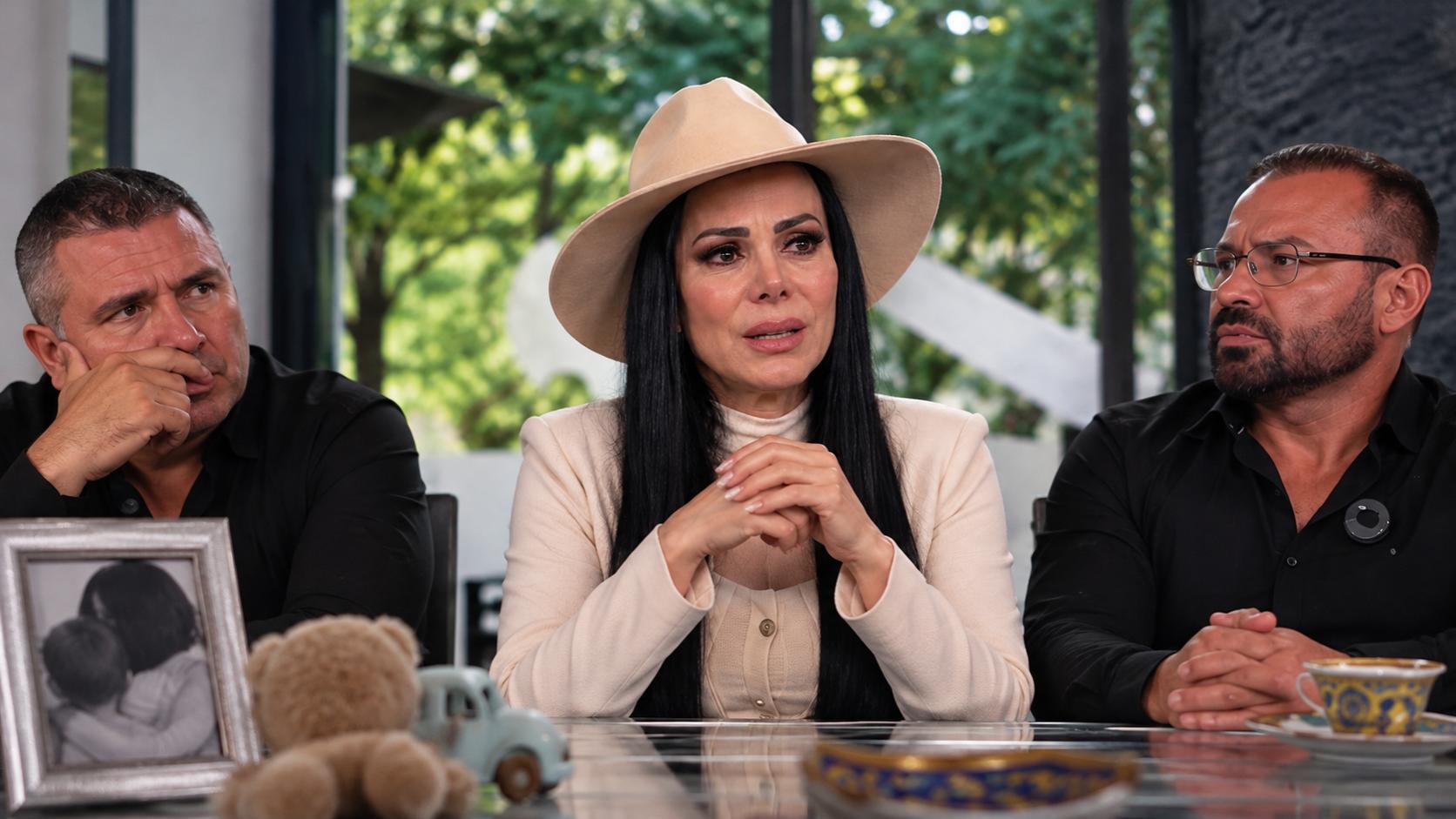 Maribel Guardia habla con expresión de tristeza durante una conversación, acompañada por dos hombres.