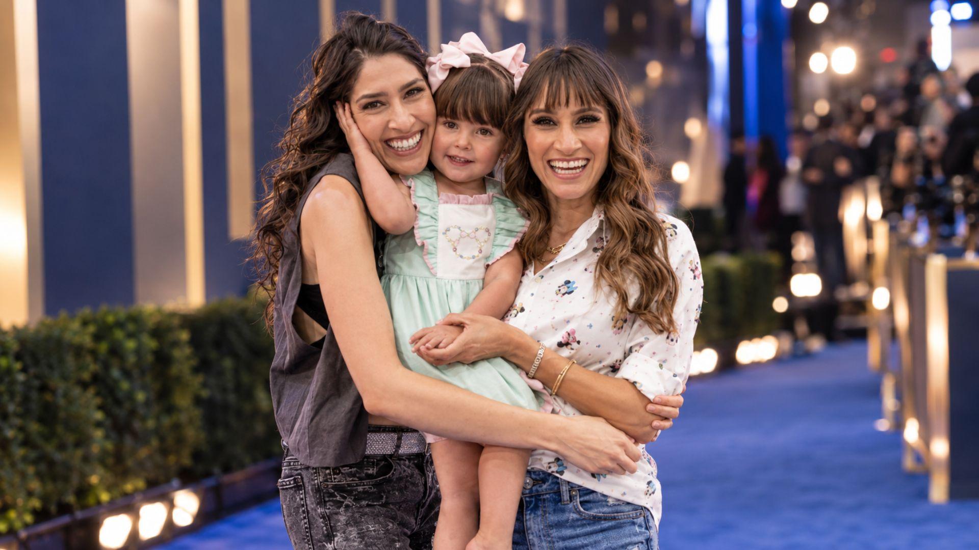 Hanna de Ha*Ash posa junto a Mathilda y Ashley en una alfombra azul, en un momento familiar y sonriente.